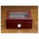 A closed small glass humidor  in cherry finish with see through glass on top and an external hygrometer displaying eleven cigars through the glass 