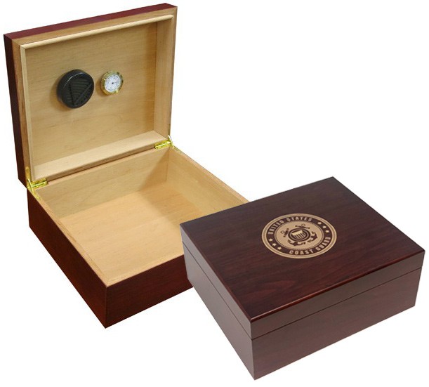 Two humidors in cherry finish one is open showing a humidifier and hygrometer the other one is closed with the US Coast Guard emblem engraved on top